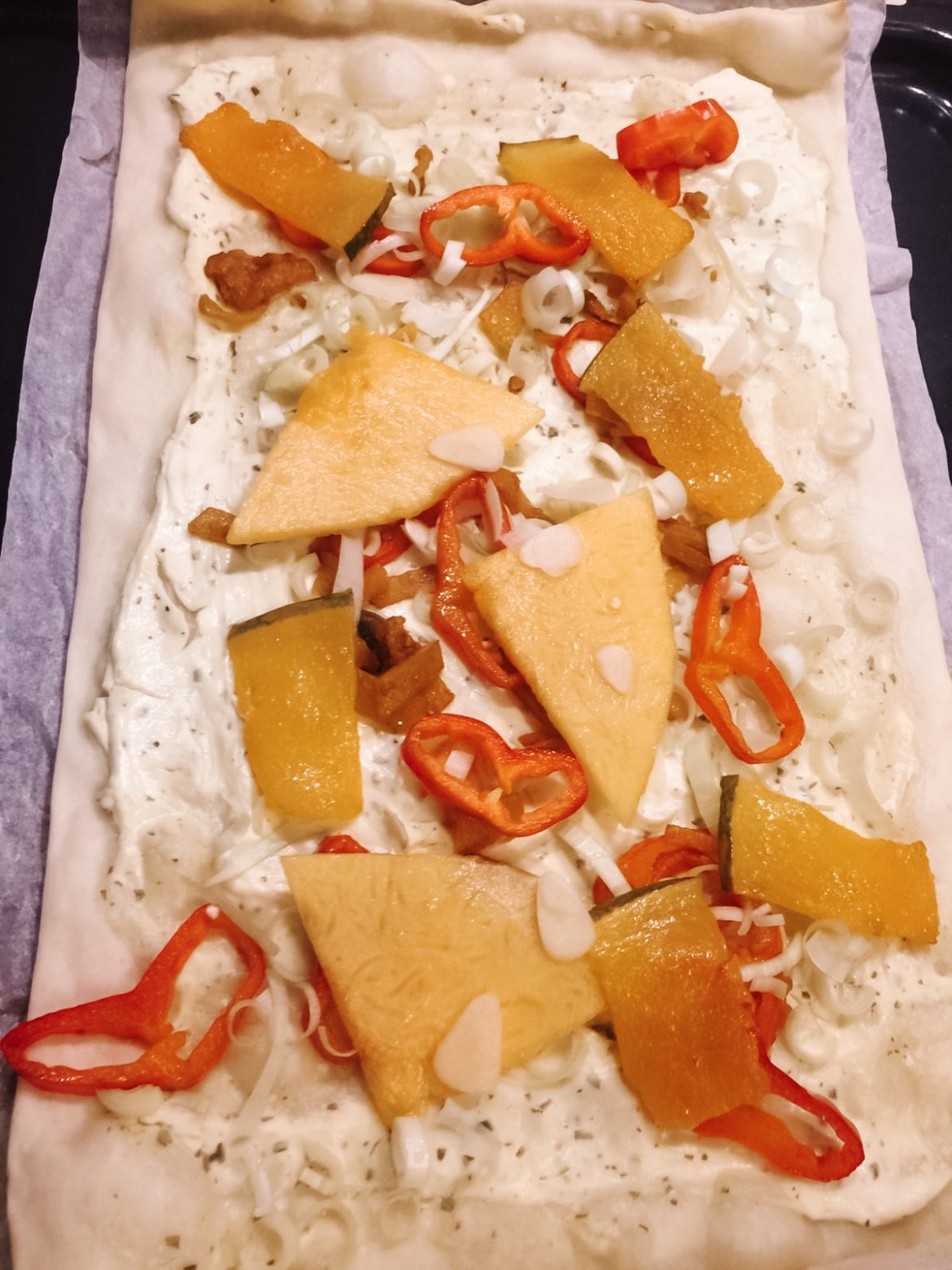 Kürbisflammkuchen Flammkuchen mit Creme Fraiche, Kürbis, rotem Paprika, Zwiebel und Knoblauch